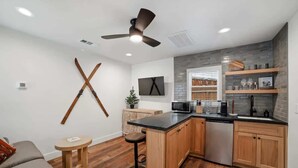 A modern kitchen with wooden cabinets, a black countertop, and a built-in microwave.
