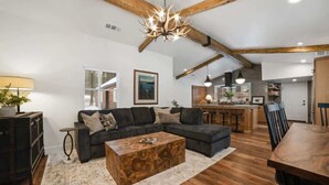 A spacious living area with a dark-colored sofa, a wooden coffee table, and a chandelier.