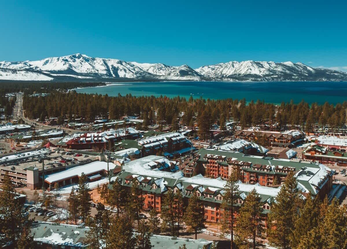 Ein Ferienresort mit mehreren Gebäuden, einem Parkplatz und Blick auf schneebedeckte Berge und einen See.