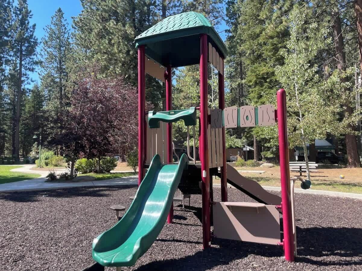 A playground with a green slide and a climbing structure.
