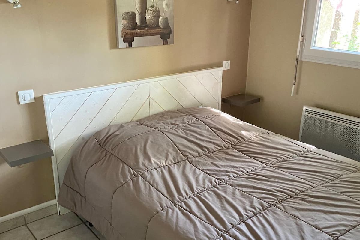 Un dormitorio con cama, una obra de arte en la pared, una ventana con persianas y un radiador.