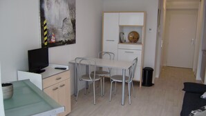 Een compacte, moderne woonruimte met een eethoek, kitchenette en een schilderij aan de muur.
