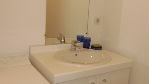 Een badkamer met een wit wastafel, spiegel en een wit toilet.
