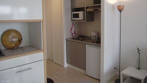 Een kleine keuken met een magnetron, spoelbak en een kastje.