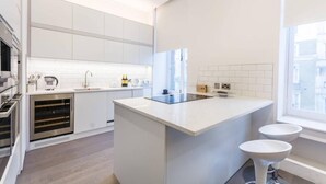 Eine moderne Küche mit weißen Schränken, einer zentralen Kochinsel und einem Fenster für natürliches Licht.