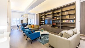 Ein modernes Wohnzimmer mit einer Couch, Sesseln, einem Couchtisch und einem Bücherregal.