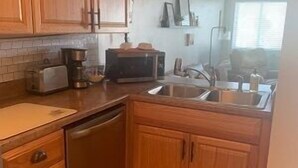 Una cocina con armarios de madera, lavavajillas, microondas y fregadero.