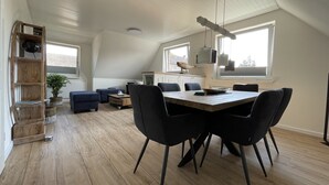 En moderne loftslejlighed med spiseplads, en sovehems og et stort vindue, der giver naturligt lys.