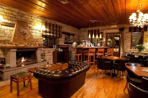 A cozy interior with a stone fireplace, leather sofa, wooden dining table, and bar area.