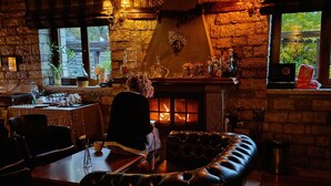 A cozy interior with a stone wall, a fireplace, and a leather sofa. - Nisista Lodge Mountain View (Arta)