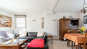 A living room with a black sofa, a wooden coffee table, a dining table with chairs, and a painting on the wall. - Ty Yann - proche plage (Carantec)