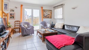 A modern living room with a black leather sofa, grey armchairs, a wooden coffee table, and a red throw blanket. - Ty Yann - proche plage (Carantec)