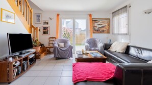 A living room with a TV, two armchairs, a sofa, a coffee table, and a staircase. - Ty Yann - proche plage (Carantec)