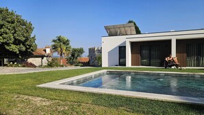 Ein modernes Haus mit Swimmingpool, Terrasse und einer Person, die am Pool entspannt.