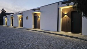 Ein modernes Gebäude mit mehreren Eingängen, die jeweils von warmem Licht beleuchtet werden.