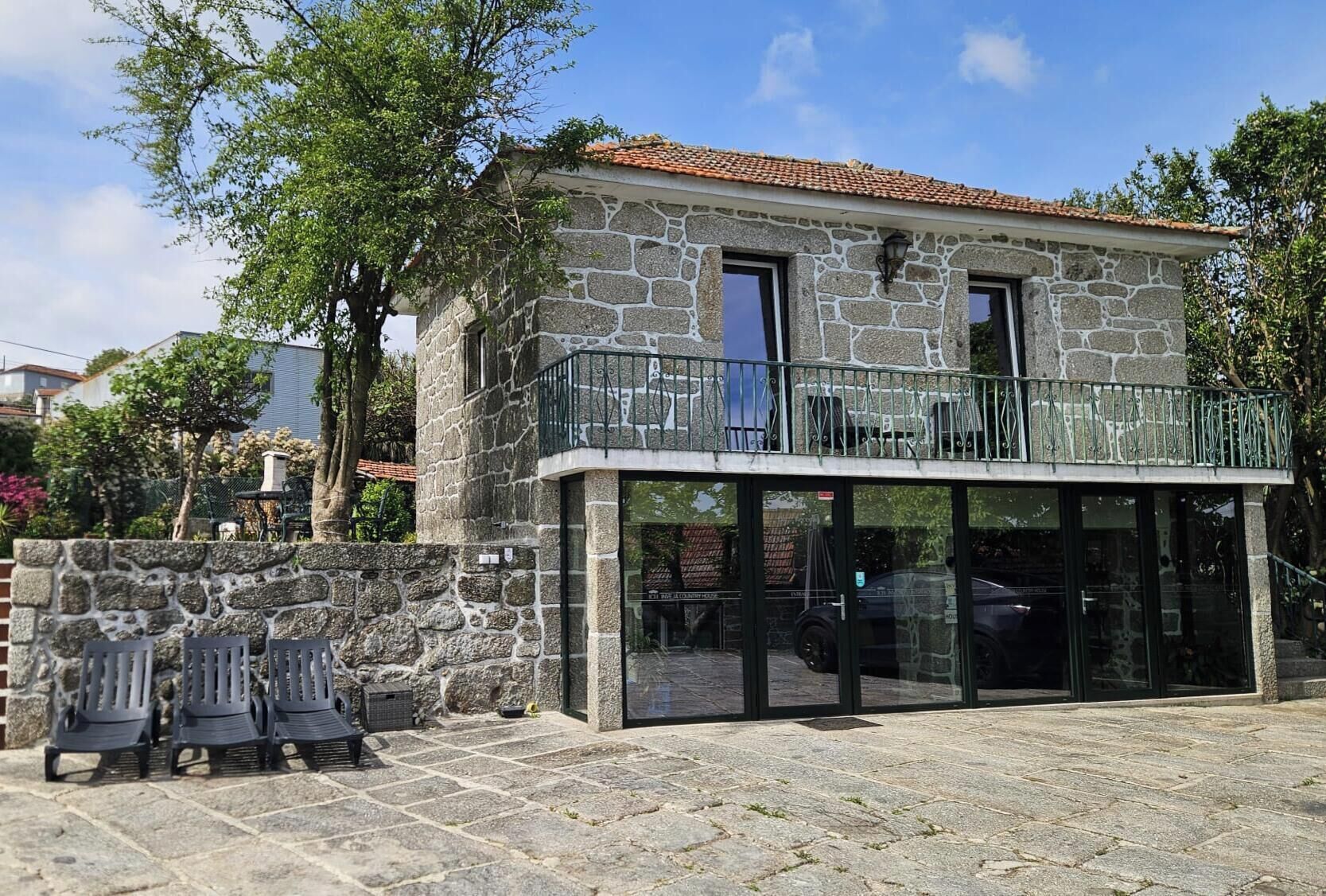 A stone building with a balcony, a covered patio, and outdoor seating.