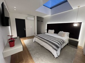 A modern bedroom with a skylight, a bed with a striped blanket, a bedside table with a red pot, and a black door. - ICH Inveja Country House (Pacos De Ferreira)