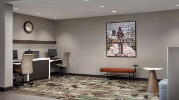 A modern office space with a desk, chairs, a bench, a round table, and a large framed artwork on the wall.