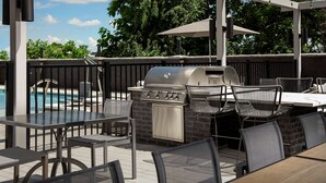 En uteplats med grill, sittplatser och en pool.
