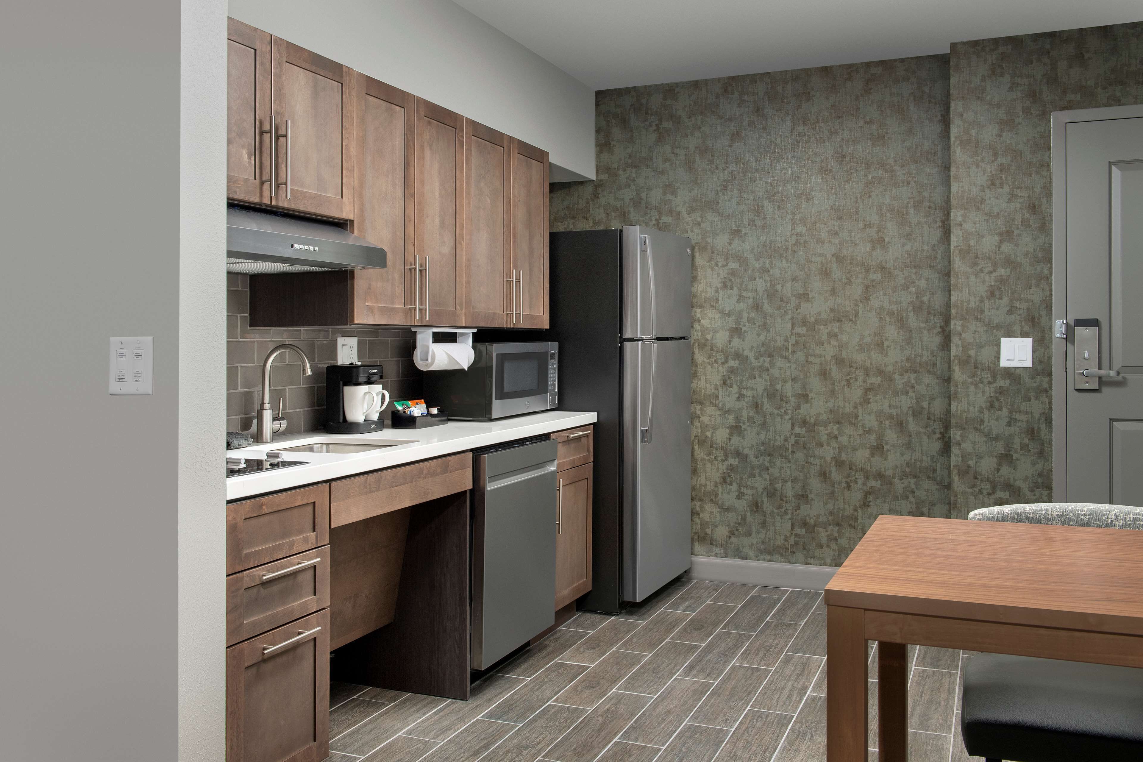A modern kitchen with wooden cabinets, stainless steel appliances, and a tiled backsplash.