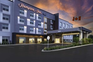 Un hotel moderno con un letrero llamativo, un estacionamiento y una bandera.