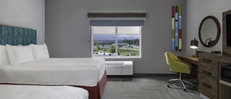 A hotel room with a large bed, a desk with a chair, a window with a view, and a mirror.