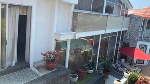 A two-story building with a balcony, large windows, and potted plants. - Beautiful Villa La Concepcion (Cuernavaca)