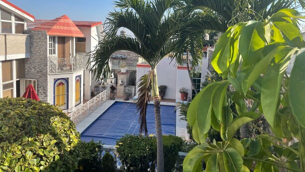 A courtyard with a swimming pool, surrounded by palm trees and potted plants. - Beautiful Villa La Concepcion (Cuernavaca)