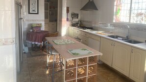 A kitchen with white cabinets, a gas stove, a sink, and a window with a floral design. - Beautiful Villa La Concepcion (Cuernavaca)