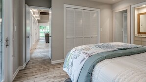 Een slaapkamer met een groot bed, een inloopkast en een gang die leidt naar een patio.