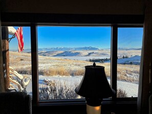 Ein Zimmer mit einem großen Fenster, das einen Blick auf eine verschneite Landschaft mit Bergen in der Ferne bietet.