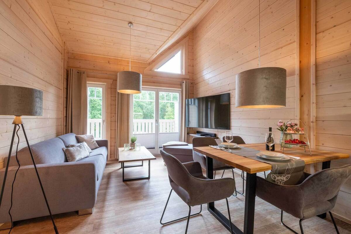 Ein gemütliches Blockhausschlafzimmer mit einer Couch, einem Esstisch, Stühlen und einem Fernseher.