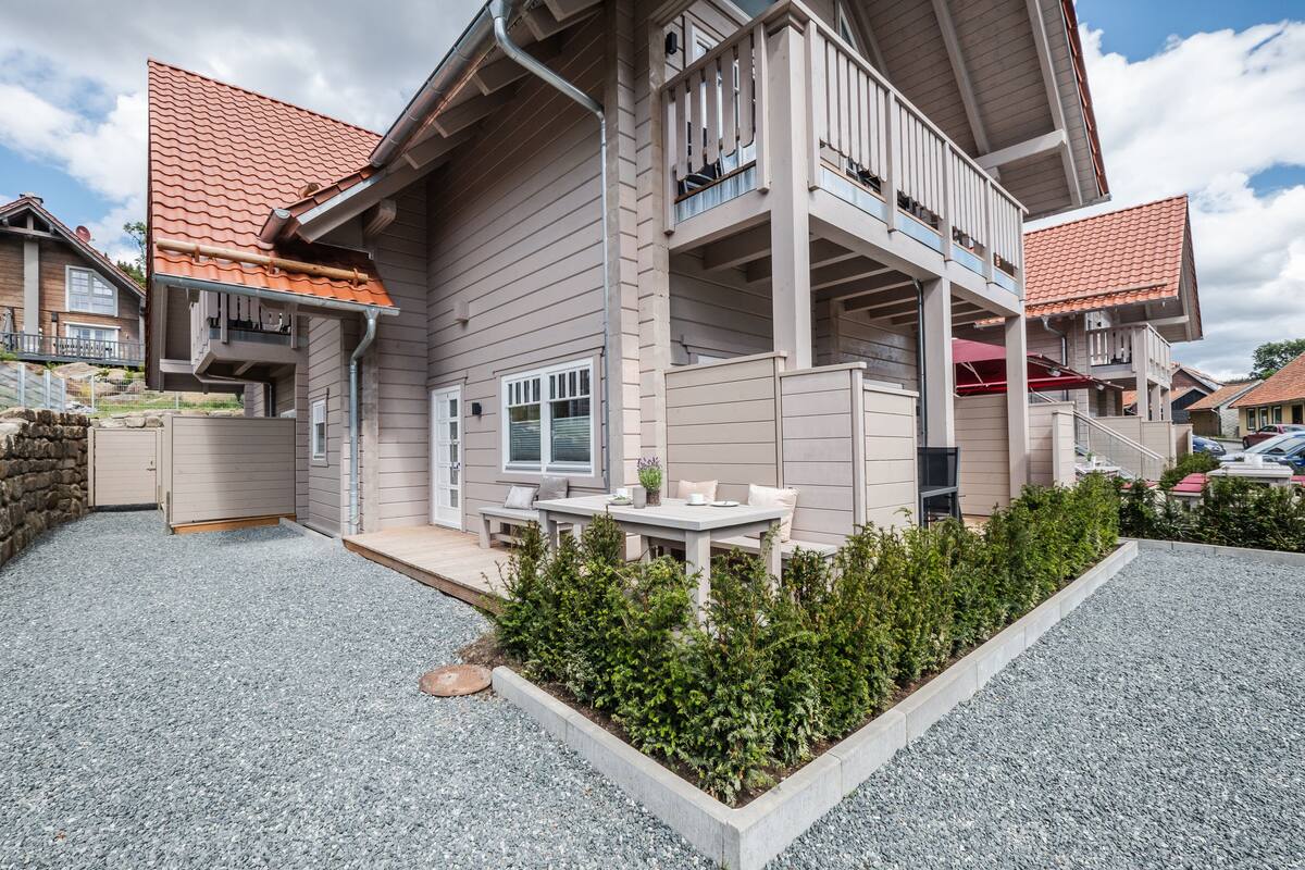 Ein zweistöckiges Haus mit Balkon, Kiesauffahrt und kleinem Garten.