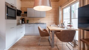 Una cucina moderna con mobili bianchi, elettrodomestici in acciaio inossidabile e un soffitto in legno.