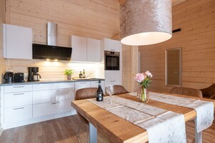 Una cocina moderna con armarios blancos, una mesa de comedor de madera y una lámpara colgante.
