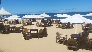 A beachside seating area with white umbrellas and wooden chairs.