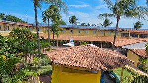 A yellow building with a tiled roof surrounded by palm trees and a well-maintained garden.