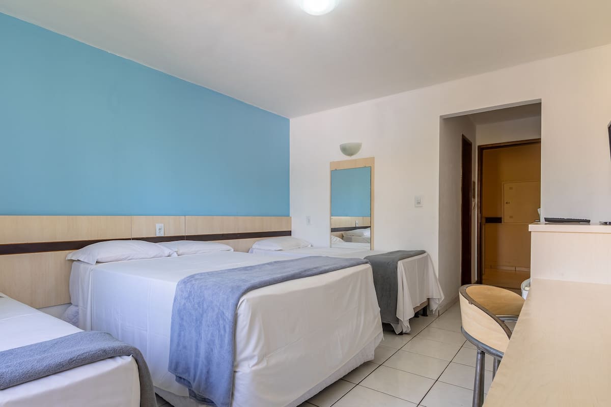 Habitación de hotel con dos camas, un escritorio y un espejo.