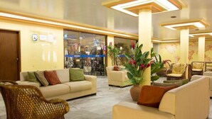 A lobby with a beige sofa, wicker chairs, and a potted plant.