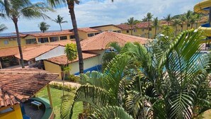 A courtyard with palm trees, a pool, and buildings with red-tiled roofs.