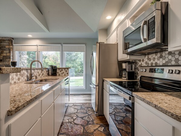 A modern kitchen with granite countertops, a built-in stove, and a microwave.