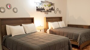 Habitación de hotel con dos camas, cabeceros de madera y un adorno decorativo sobre las camas.
