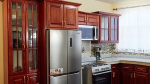 Una cocina con armarios de madera, un refrigerador de acero inoxidable, un microondas y un horno.