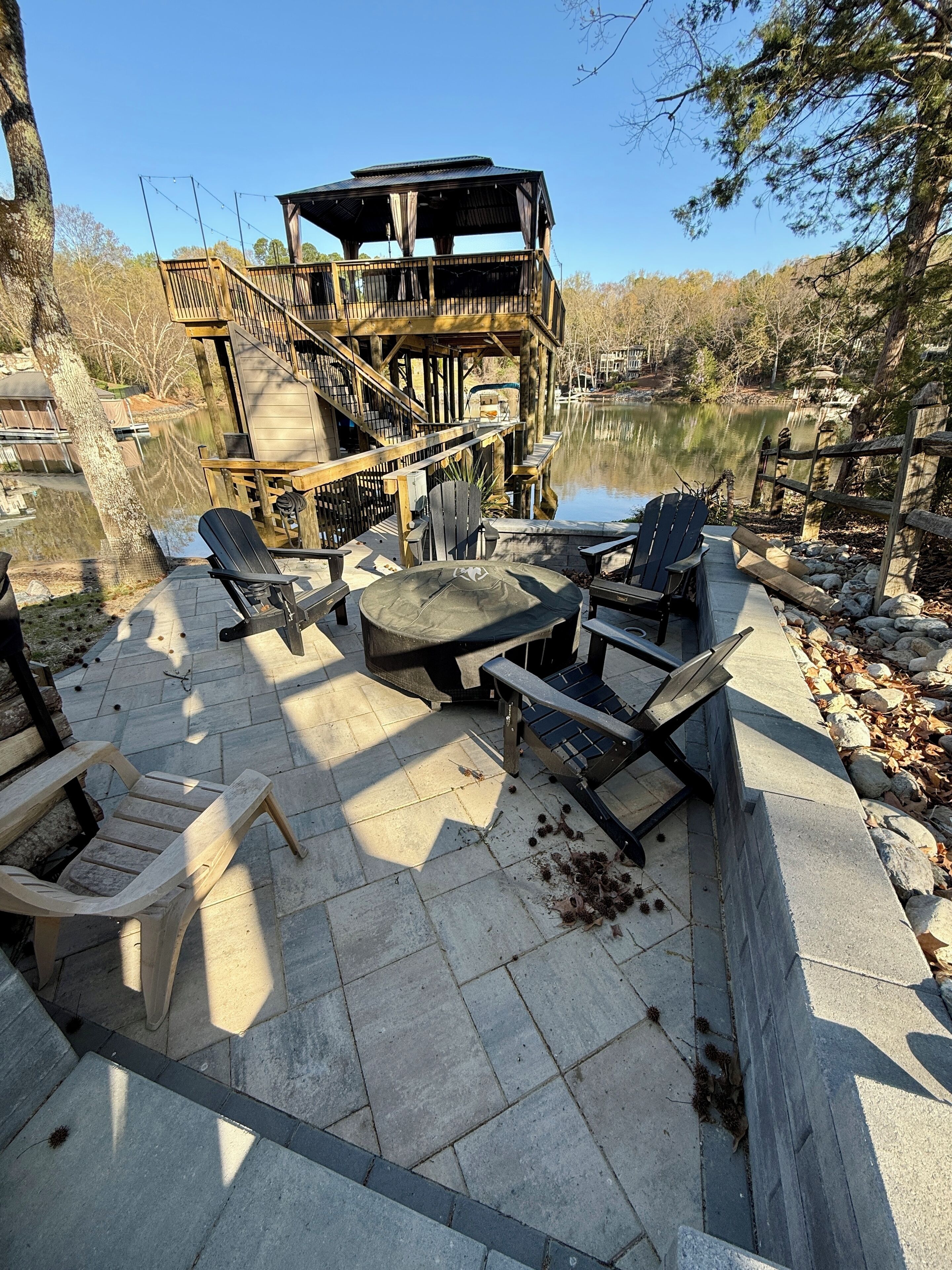 Une terrasse en bois avec des chaises Adirondack et une table, donnant sur un lac.