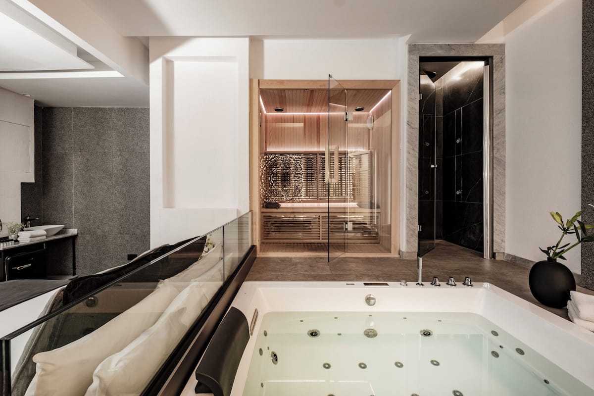 A modern bathroom with a large bathtub, a glass-enclosed shower, and a wooden vanity.