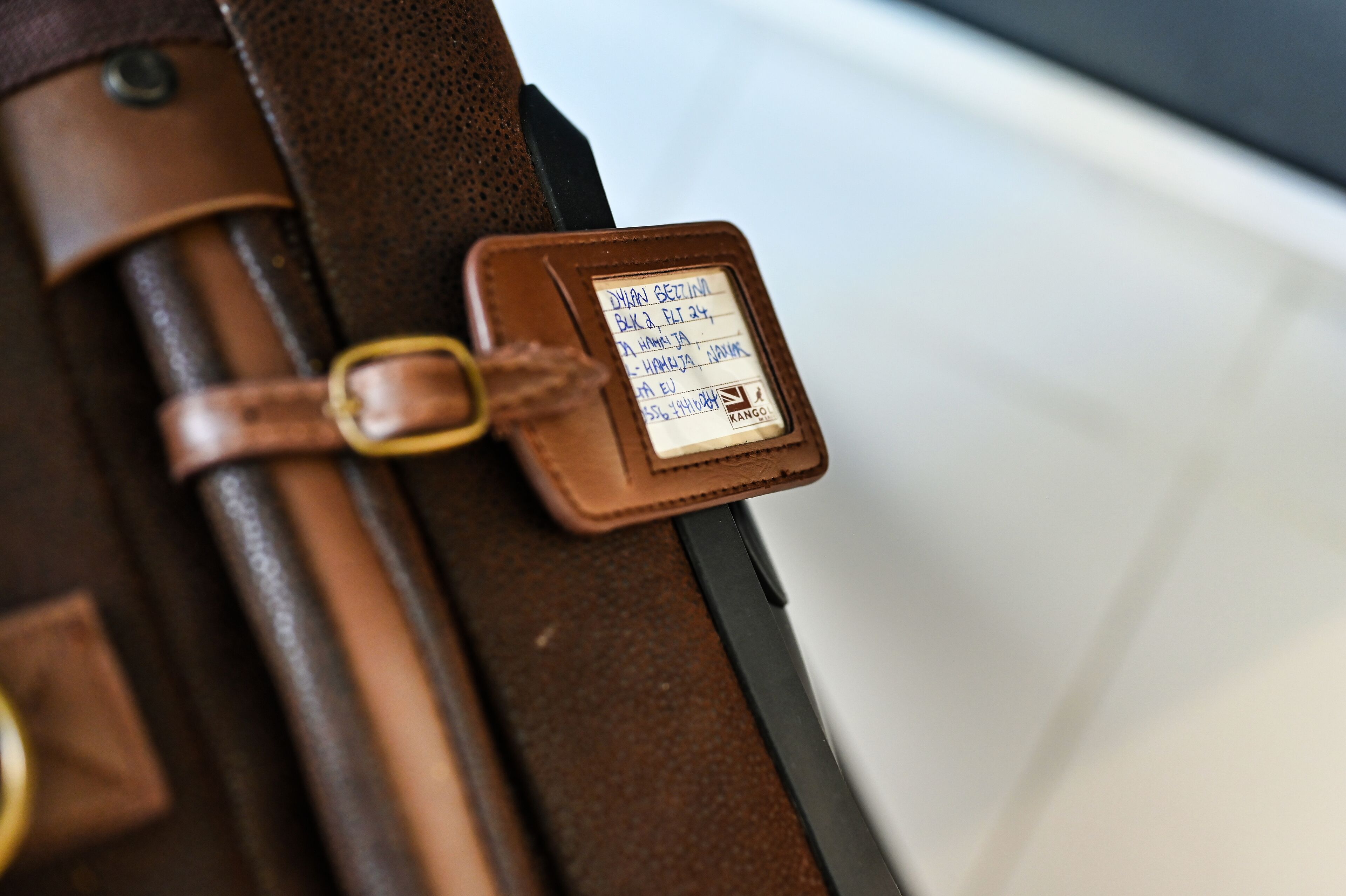 A brown leather suitcase with a metal clasp and a tag attached.