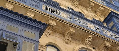 A multi-story building with ornate architectural details, including decorative moldings and a balcony with intricate railings.