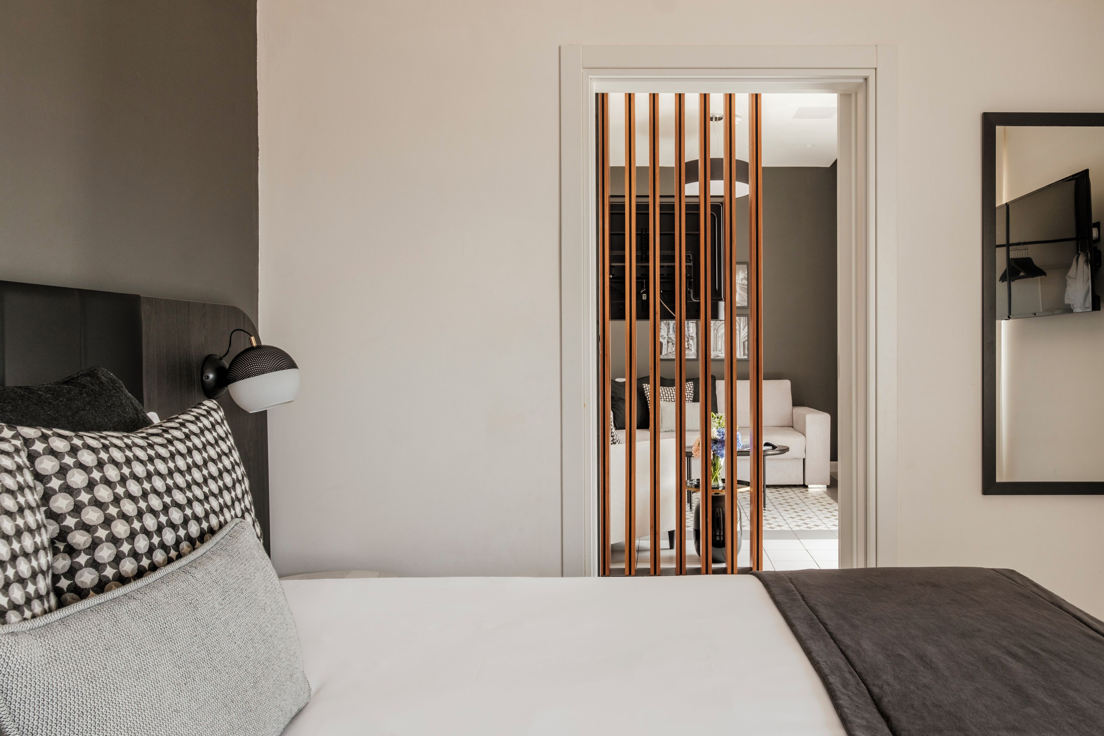 A bedroom with a bed, a nightstand, a lamp, a wardrobe, and a mirror.