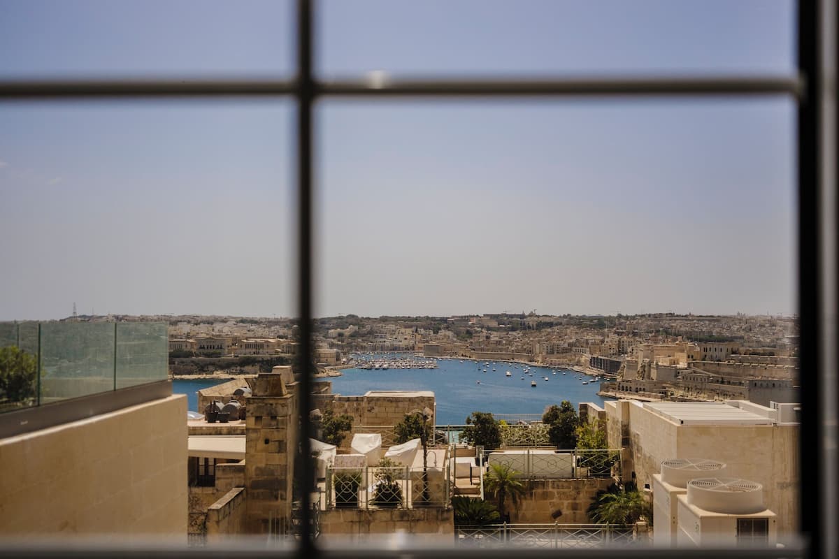 A coastal cityscape viewed through a window with a clear view of the harbor, buildings, and a distant power line.