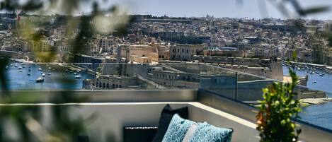 A balcony with a view of a harbor, featuring boats and a historic cityscape.